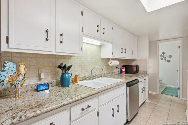 a kitchen with white cabinets and sink