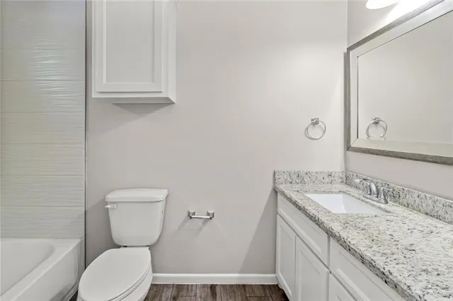 a bathroom with a granite countertop toilet sink and mirror