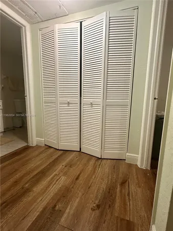 an empty room with wooden floor and closet area