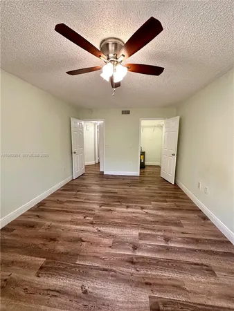 a view of empty room with wooden floor and fan