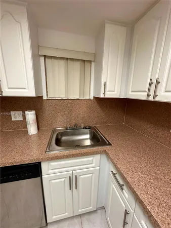 a kitchen with granite countertop cabinets sink and washing machine