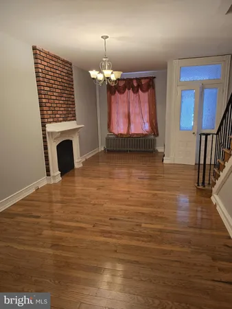 an empty room with wooden floor windows and a fireplace