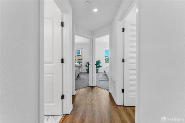 a view of a hallway with wooden floor and a bathroom
