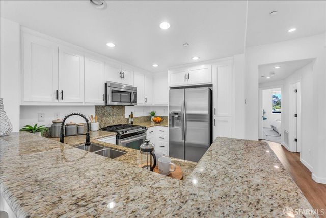 a kitchen with stainless steel appliances granite countertop a refrigerator and a sink