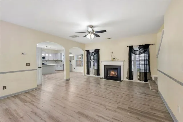 a view of a livingroom with a fireplace a ceiling fan a fireplace and windows