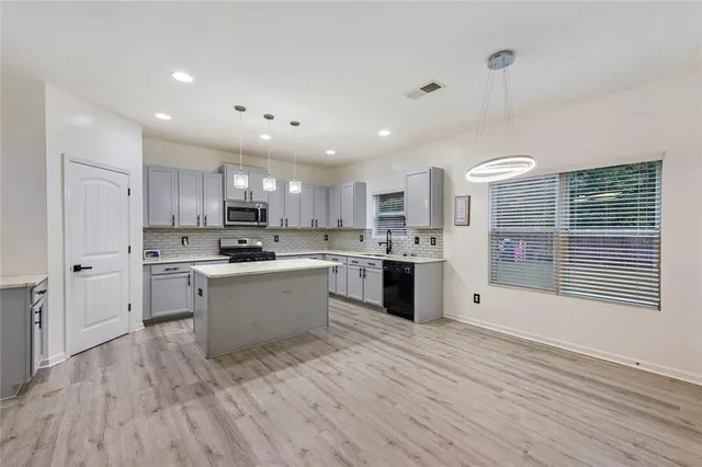 a large kitchen with kitchen island a sink a center island stainless steel appliances and a window