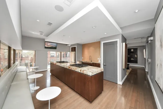 a kitchen with stainless steel appliances granite countertop a stove a sink a microwave a dining table and chairs with wooden floor