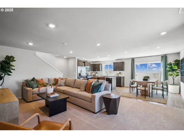 a living room with furniture potted plant and kitchen view