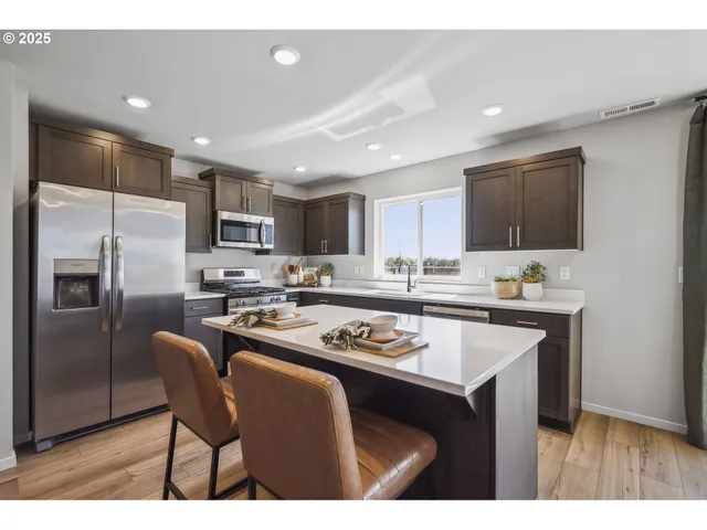 a kitchen with kitchen island white cabinets a refrigerator a stove a sink and a refrigerator