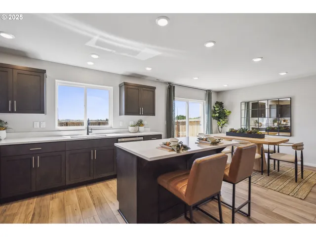 a kitchen with stainless steel appliances granite countertop wooden cabinets a dining table and chairs