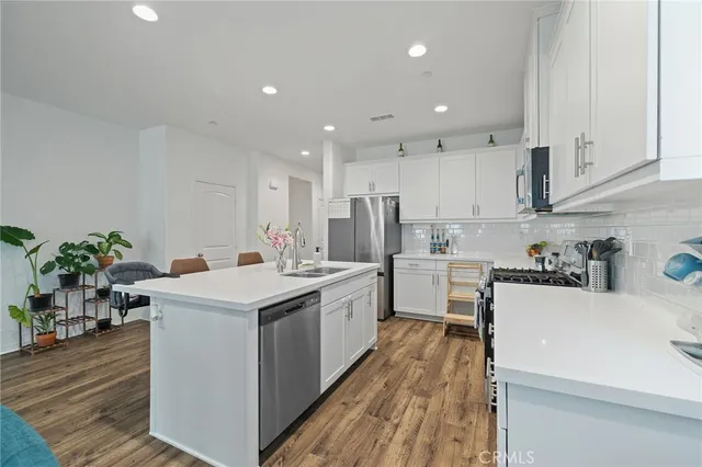 a kitchen with a sink stove cabinets and wooden floor