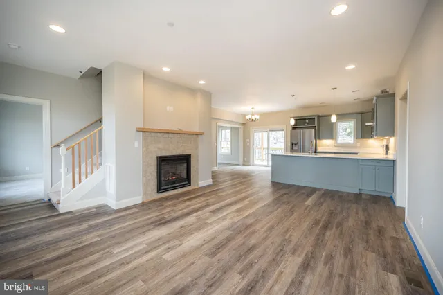 an empty room with wooden floor fireplace and windows