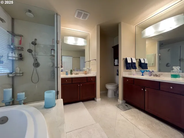 a bathroom with a tub a sink double vanity and a mirror