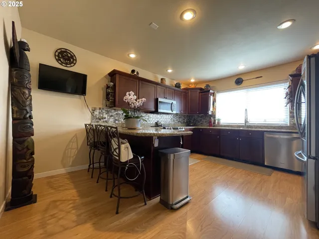 a kitchen with stainless steel appliances kitchen island granite countertop a stove a sink a refrigerator and a microwave