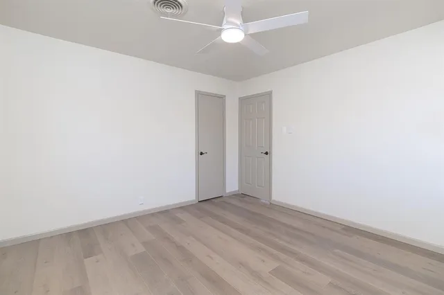 an empty room with a fan & a ceiling fan