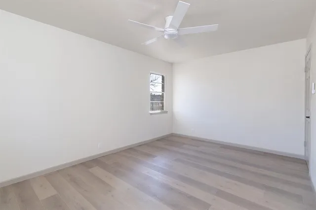 an empty room with a window and a ceiling fan