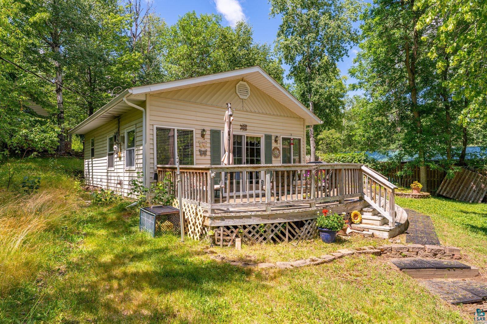 View of front of house featuring a deck and view of scattered trees