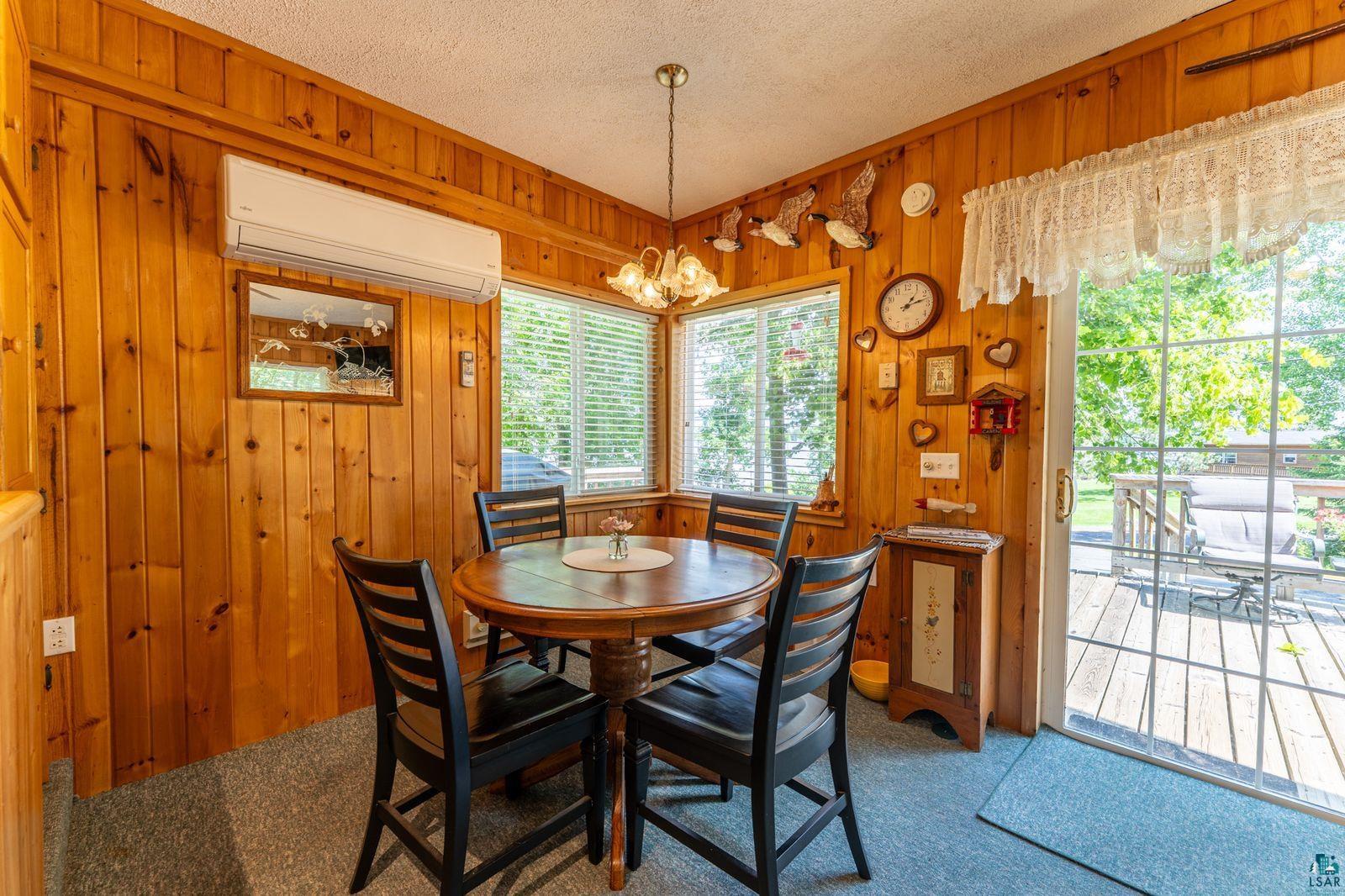 3609 Fectos Road Tower, MN 55790 - Photo 3 of 24 Dining room featuring a chandelier, carpet flooring, a textured ceiling, and wooden walls
