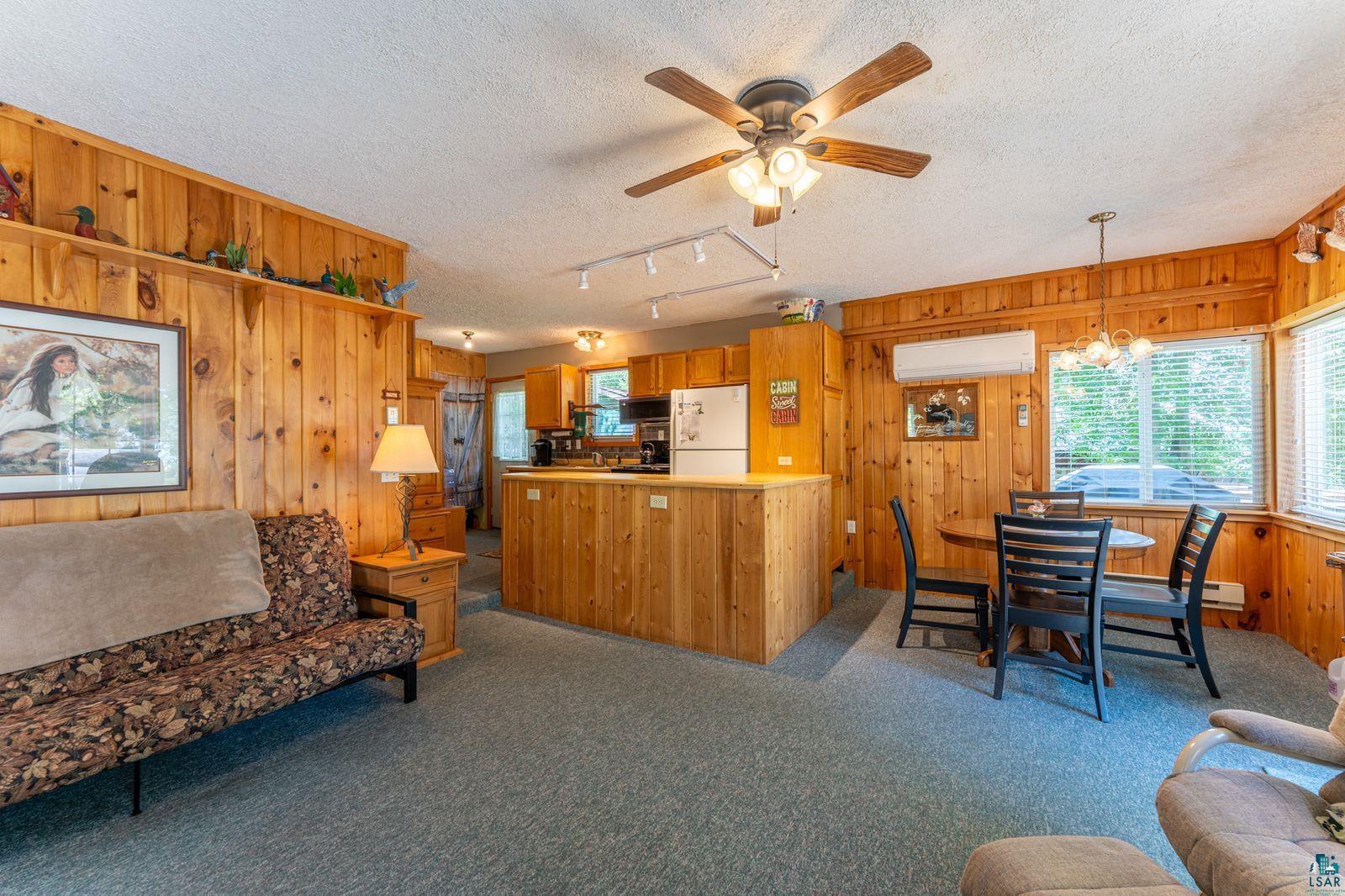 3609 Fectos Road Tower, MN 55790 - Photo 6 of 24 Living room featuring wooden walls, ceiling fan, a textured ceiling, dark carpet, and suspended lighting