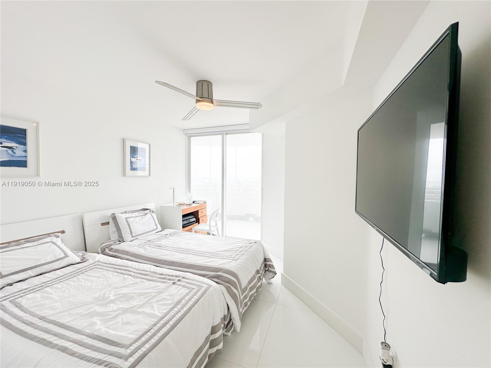 6301 Collins Avenue, Unit 2707 Miami Beach, FL 33141 - Photo 21 of 38 a bedroom with a bed and a flat screen tv