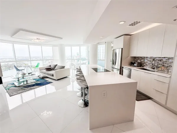 a living room with stainless steel appliances kitchen island granite countertop a sink and cabinets