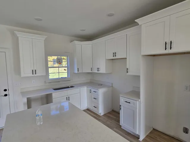 a kitchen with stainless steel appliances granite countertop a sink a stove and white cabinets