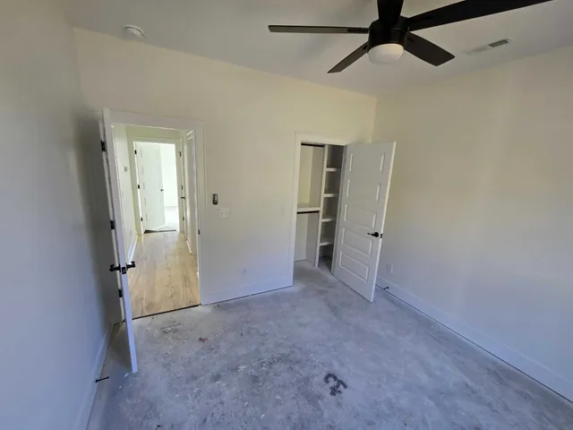 an empty room with closet and a ceiling fan