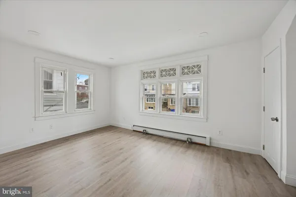 a view of an empty room with a window and wooden floor