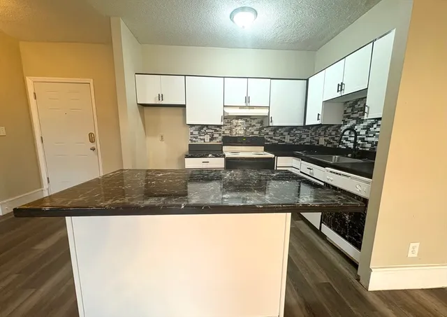 a kitchen with kitchen island granite countertop a sink stove and cabinets