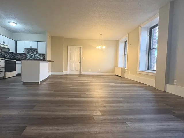 a view of kitchen and empty room with wooden floor