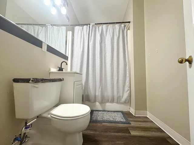 a bathroom with a toilet a sink and wooden floor