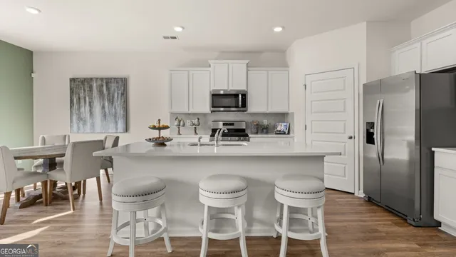 a kitchen with a dining table chairs refrigerator and microwave