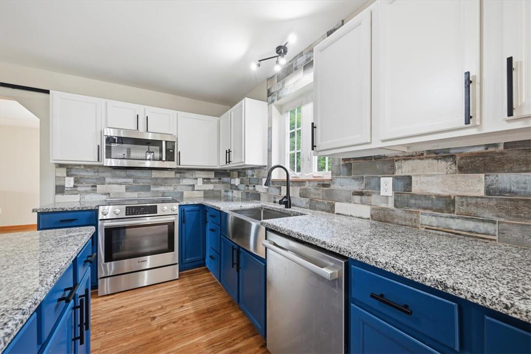 387 Blue Ridge Road Saylorsburg, PA 18353 - Photo 23 of 90 A well-appointed kitchen features vibrant blue lower cabinetry, granite countertops, and stainless steel appliances.