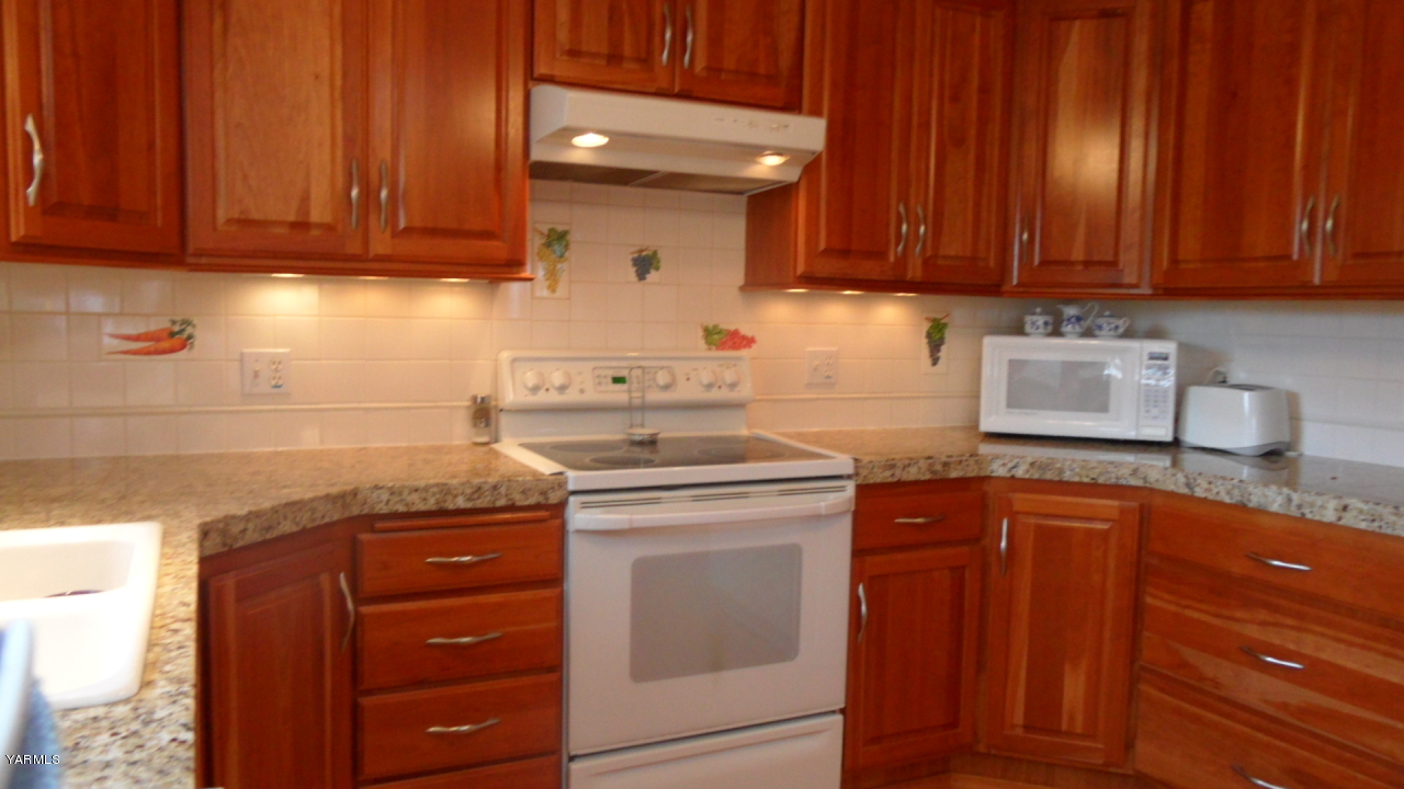 211 East Duffield Road Moxee, WA 98936 - Photo 32 of 34 a kitchen with granite countertop wooden cabinets and white appliances