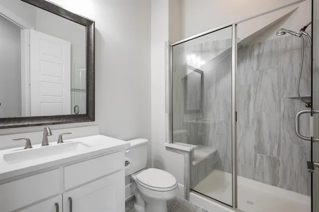 a bathroom with a shower sink vanity mirror and toilet
