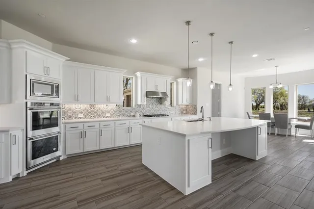 a kitchen with stainless steel appliances granite countertop a sink stove and wooden floor