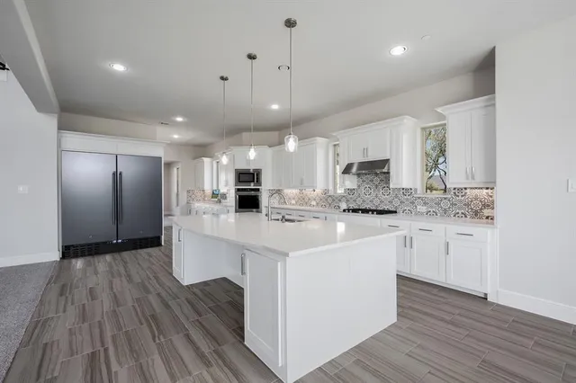 a large white kitchen with kitchen island a sink dishwasher a refrigerator oven a stove with wooden floors