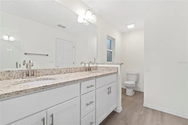 a bathroom with a granite countertop sink mirror and toilet