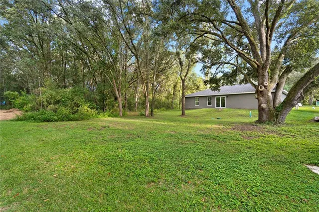 a view of a house with backyard and trees