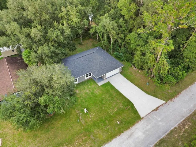 a aerial view of a house with a yard and large trees