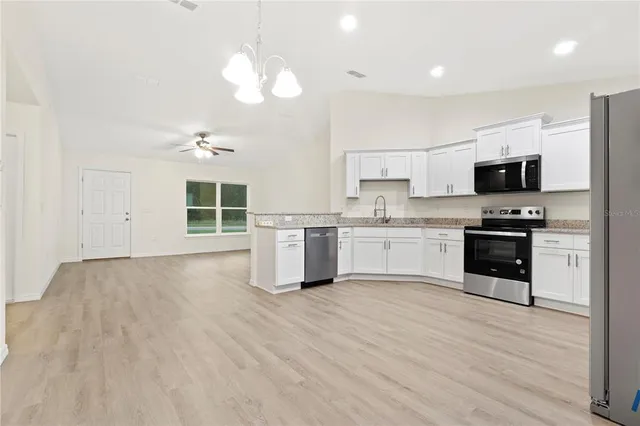 a kitchen with stainless steel appliances a stove top oven a sink dishwasher and a refrigerator with wooden floor