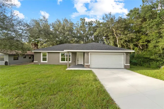 a front view of house with yard and trees in the background