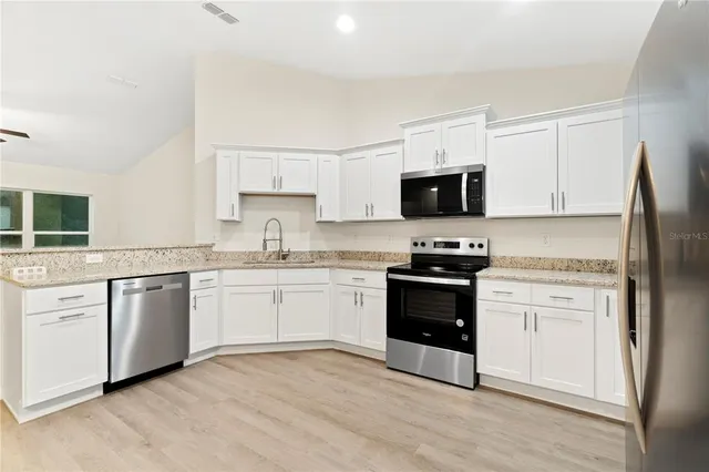 a kitchen with granite countertop white cabinets and stainless steel appliances