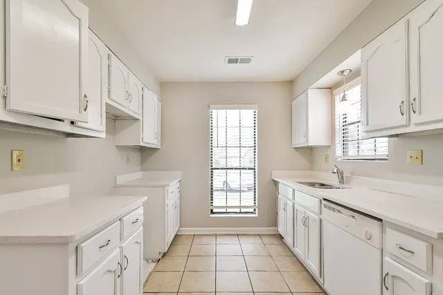 a kitchen with granite countertop white cabinets white appliances a sink and a window