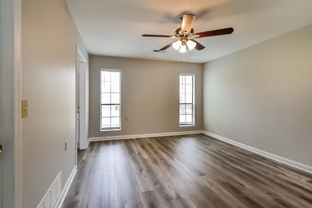 a view of an empty room with wooden floor and a window