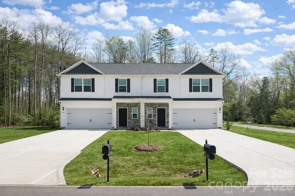 a view of a white house with a big yard and potted plants