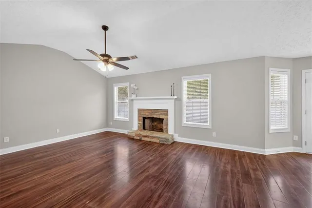 a view of a livingroom with a fireplace a window and wooden floor