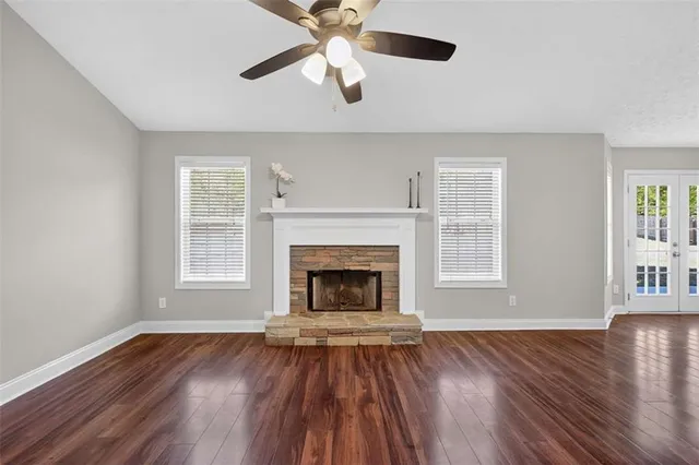 a view of an empty room with wooden floor fireplace and a window