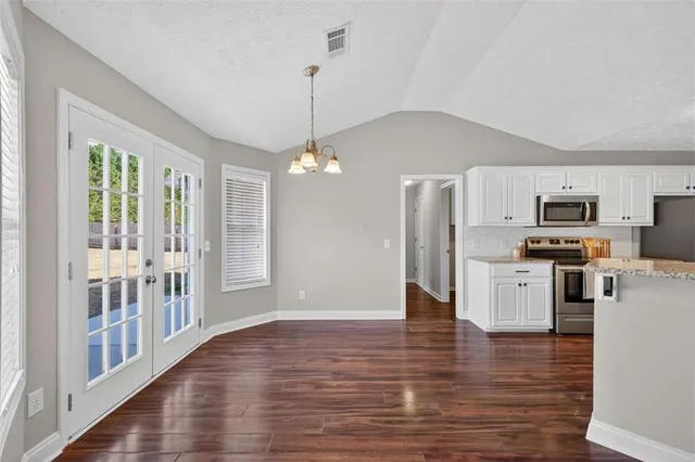 a open kitchen with stainless steel appliances granite countertop a refrigerator stove top oven and cabinets with wooden floor