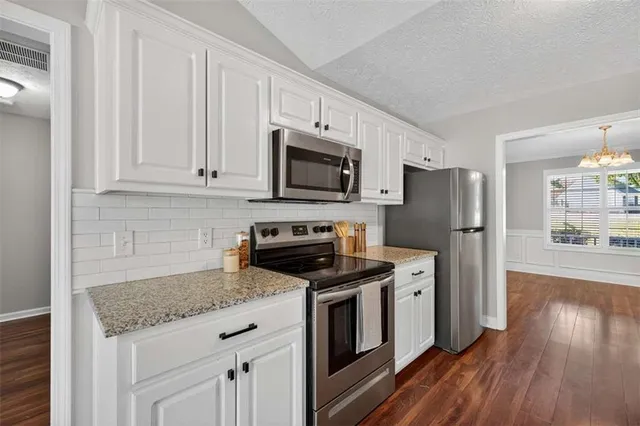 a kitchen with granite countertop a refrigerator stove and microwave